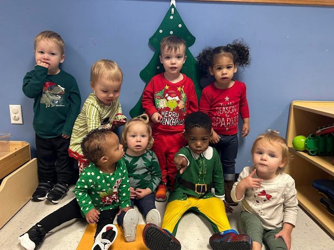 A group of children are posing for a picture in front of a christmas tree.