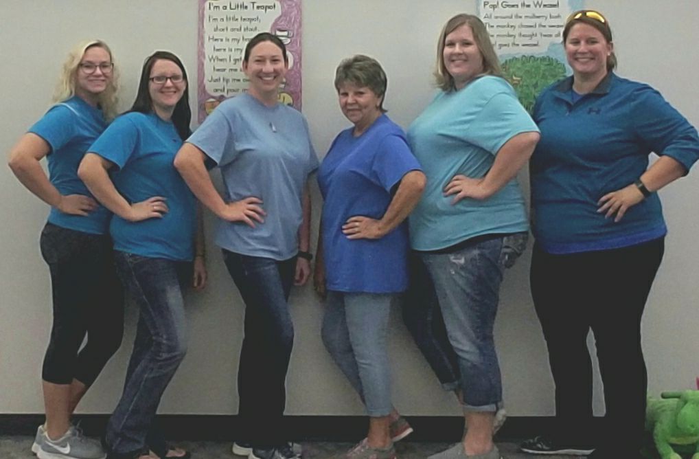 A group of women in blue shirts are posing for a picture