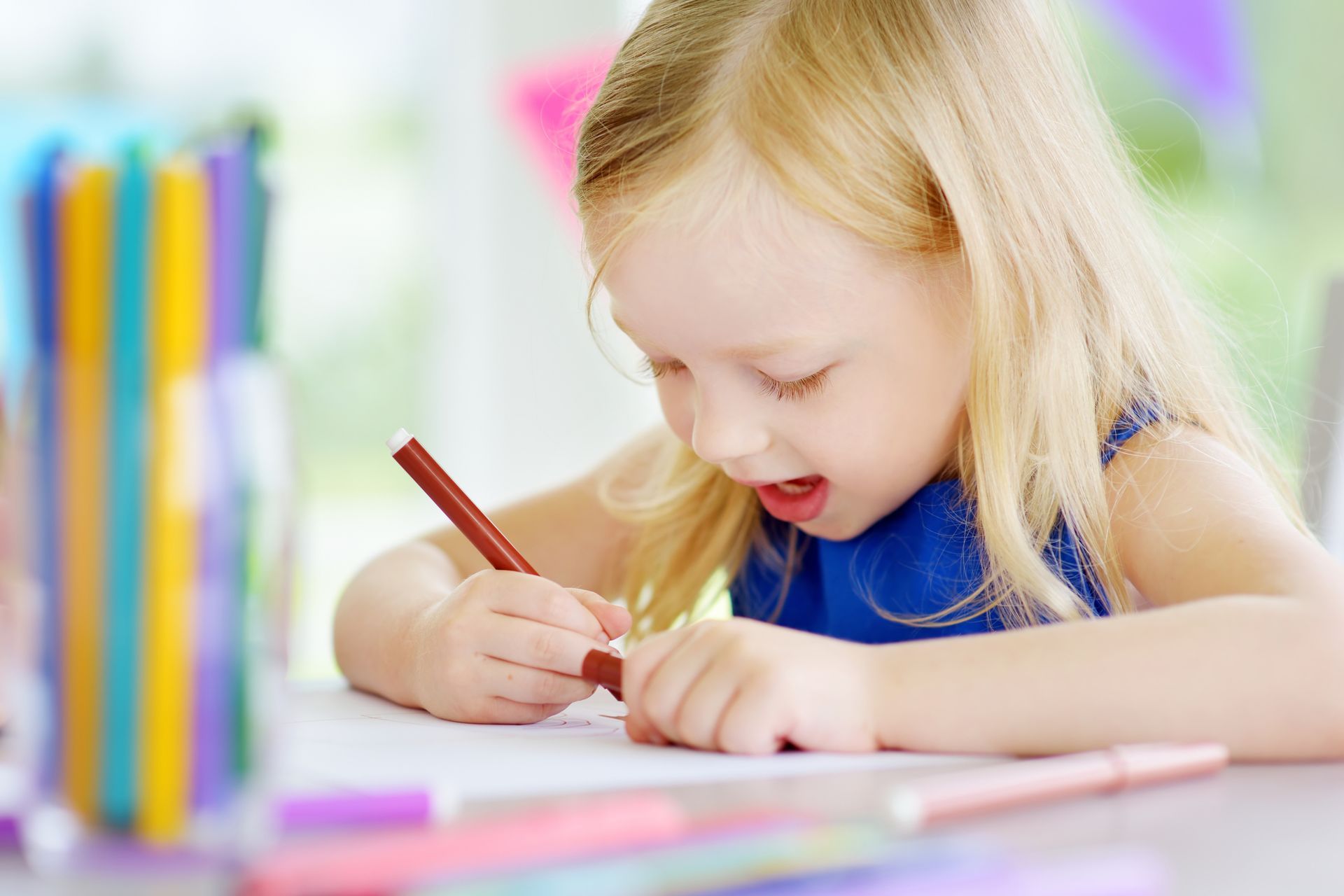 A little girl is drawing with colorful pencils at a childcare agency. A little girl is drawing with colorful pencils at a childcare agency.