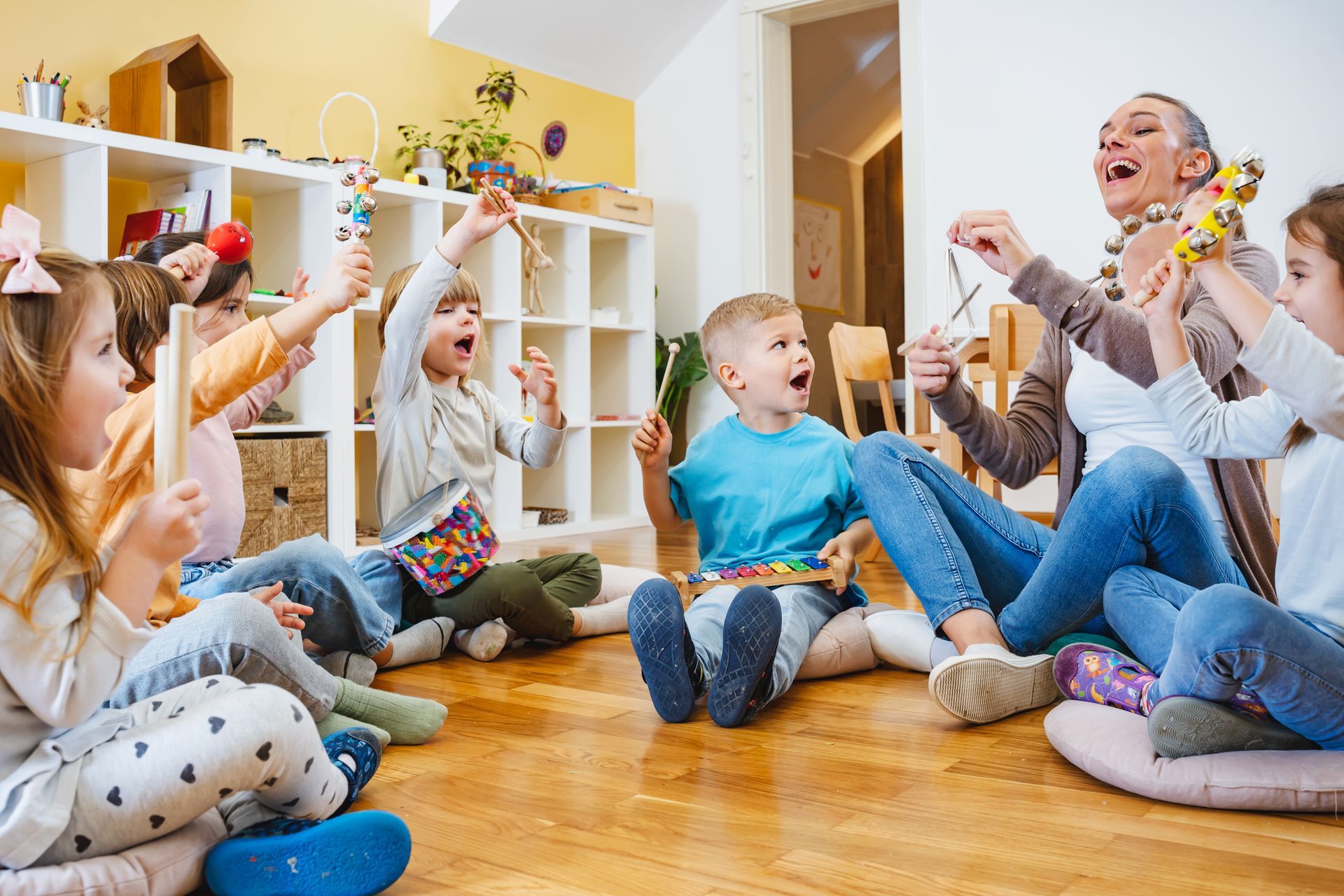 A teacher with children sitting on the floor, having a music class, at a day care agency.