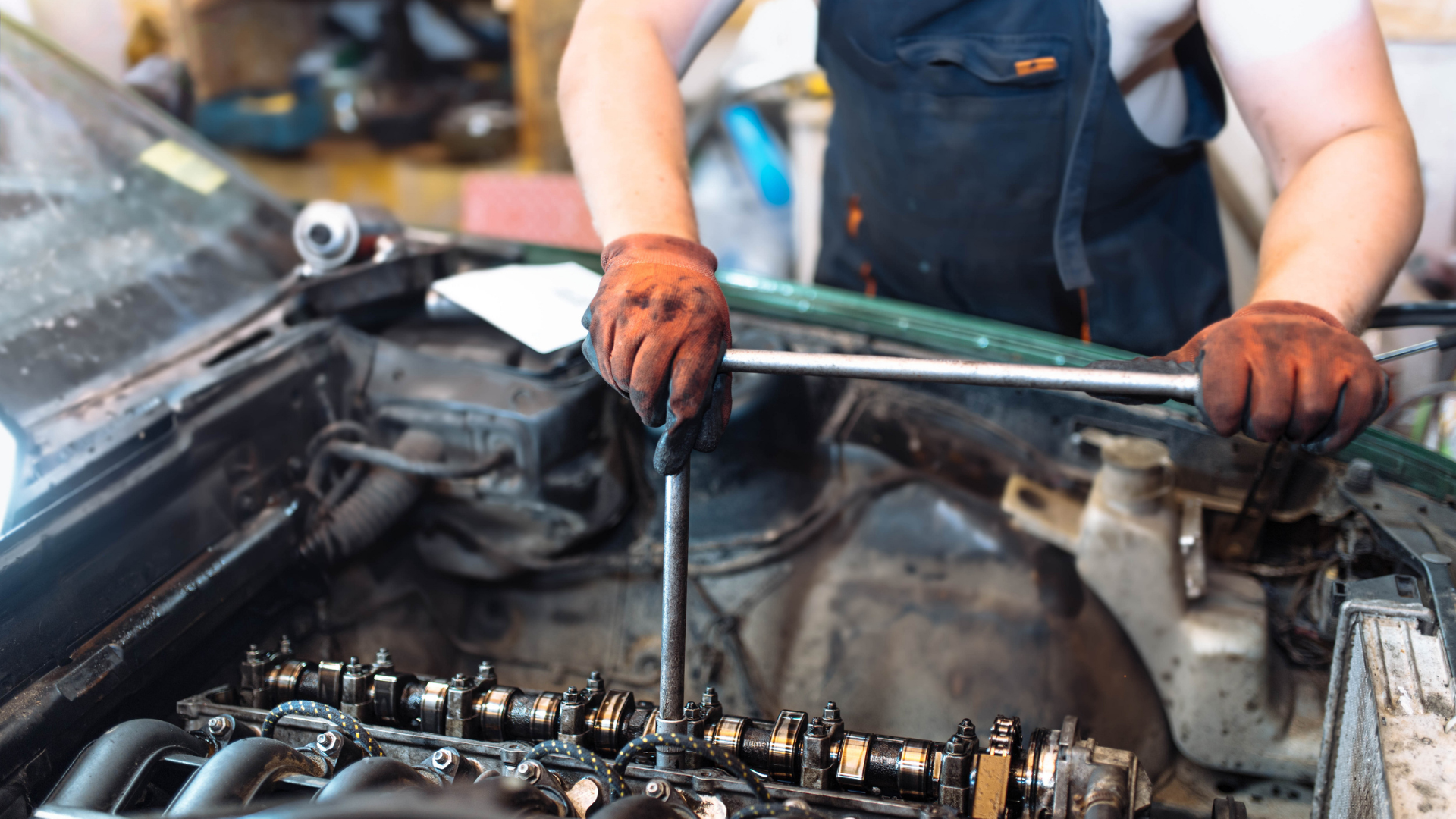 A man is working on a car engine with a wrench.