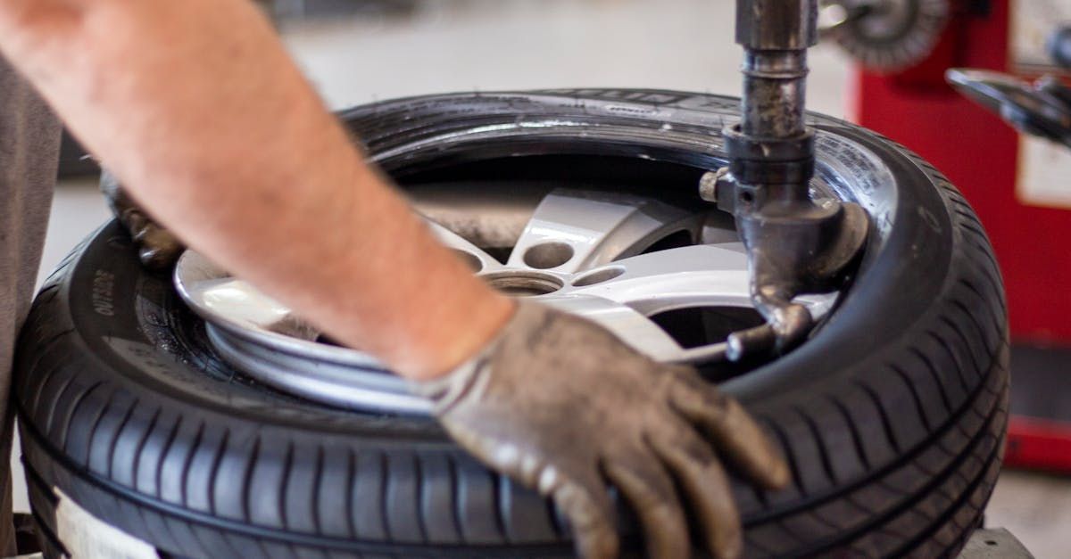 A man is changing a tire on a machine in a garage.