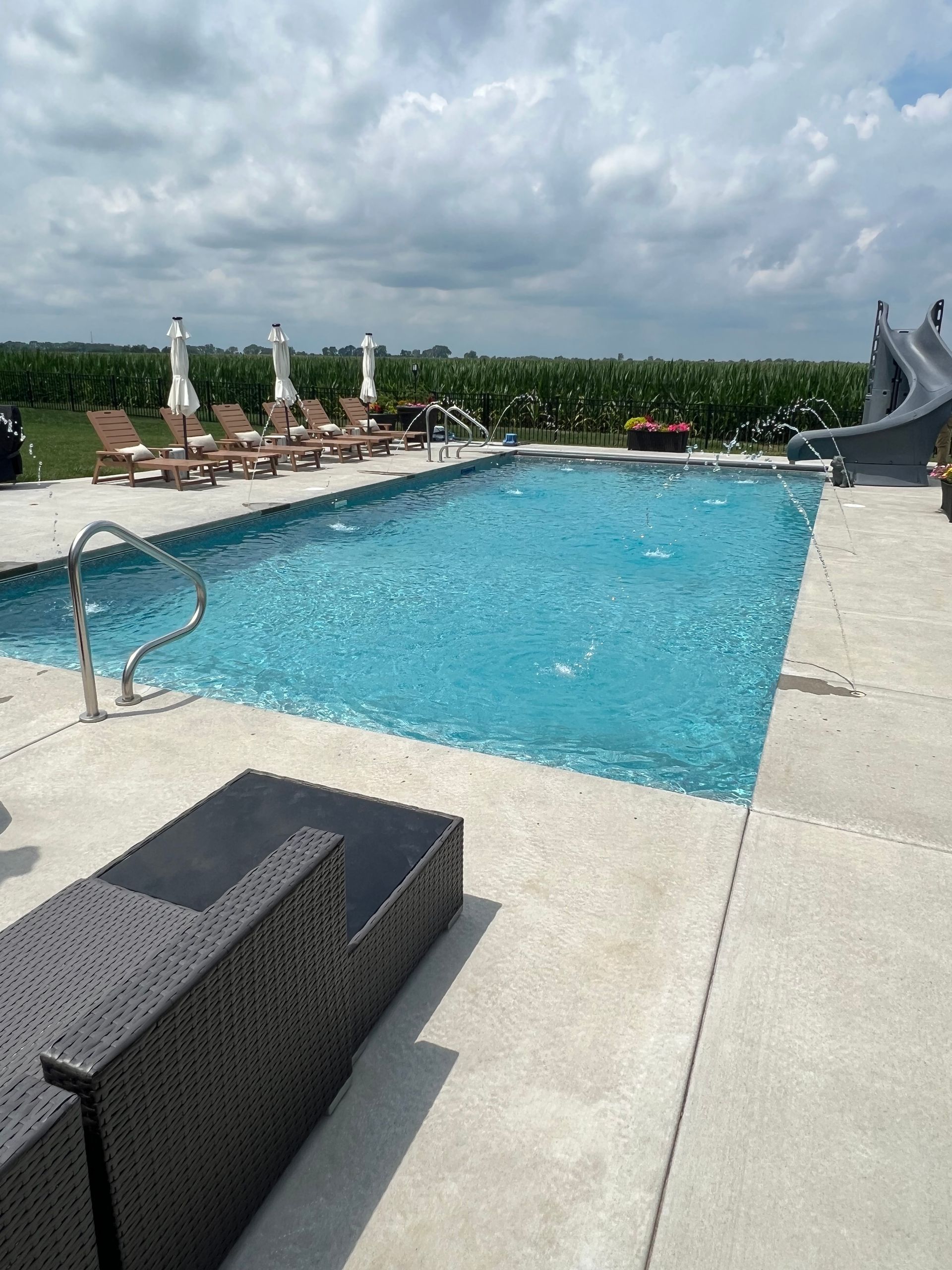 Pool with lounge chairs, umbrellas, and a slide on a sunny day.