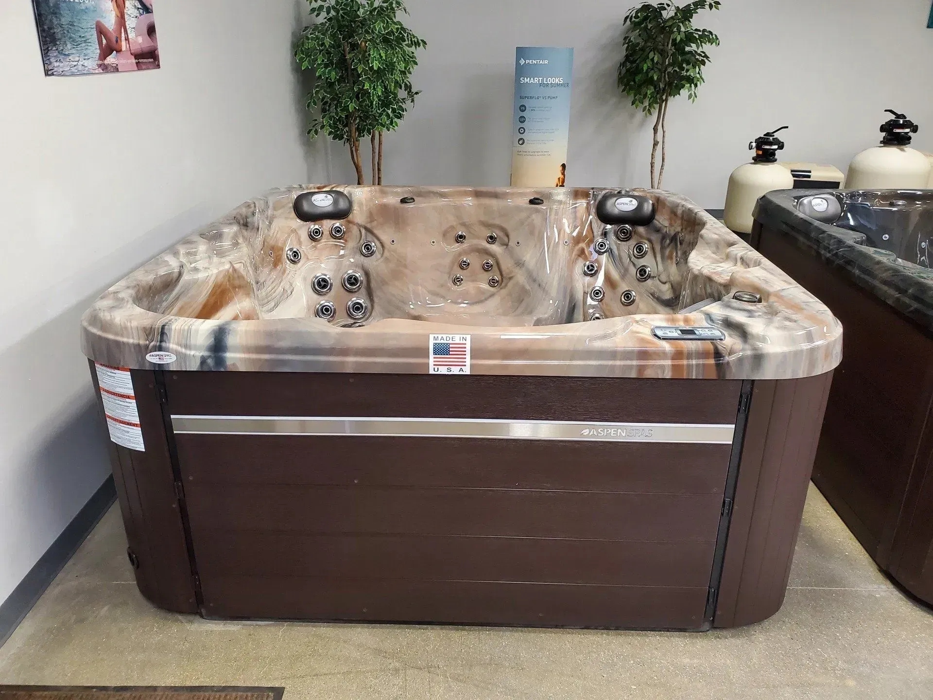 Brown hot tub on display in a store, with water jets and dark brown cabinet.