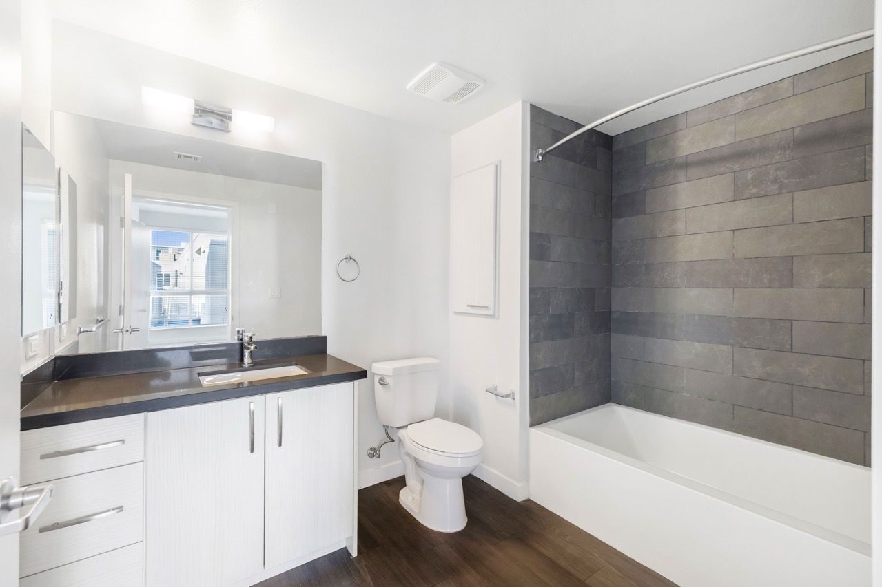 Modern apartment bathroom with vanity, toilet, and tiled tub/shower.
