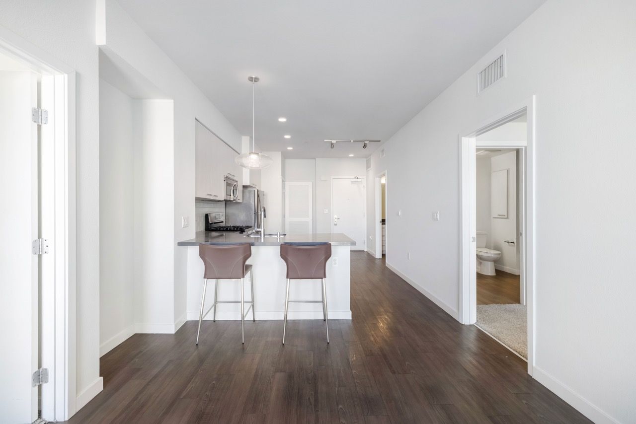 Open-concept kitchen in a modern apartment with an island and two bar stools.