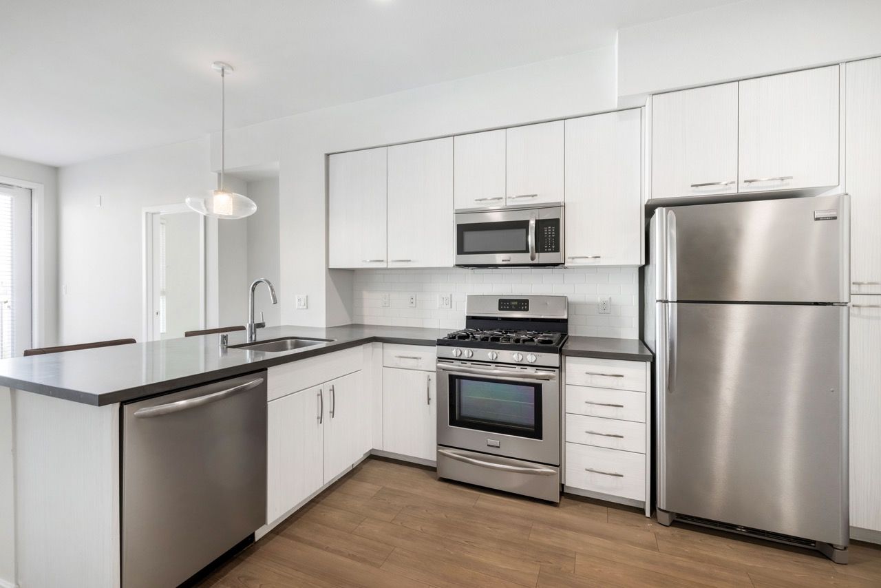 Modern kitchen with white cabinets, stainless steel appliances, and a large island.