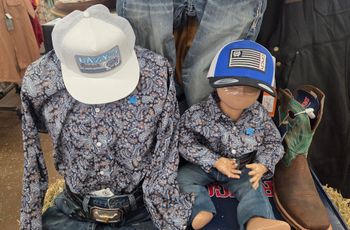Two matching floral outfits and caps displayed on mannequins, one adult-sized and one child-sized.