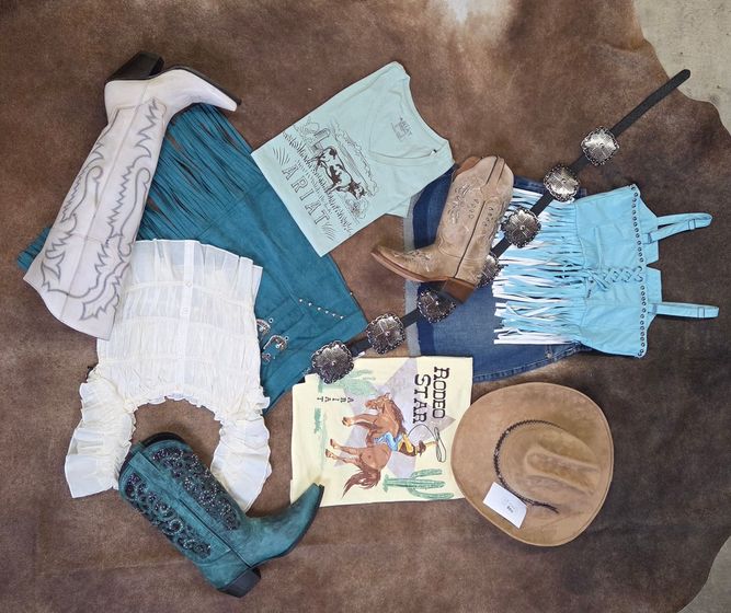 Assorted blue and beige handmade clothing items, scarves, and hats laid out on a brown surface.