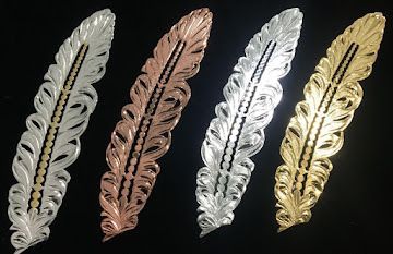 Four decorative feather-shaped ornaments in silver, copper, chrome, and gold on a black background
