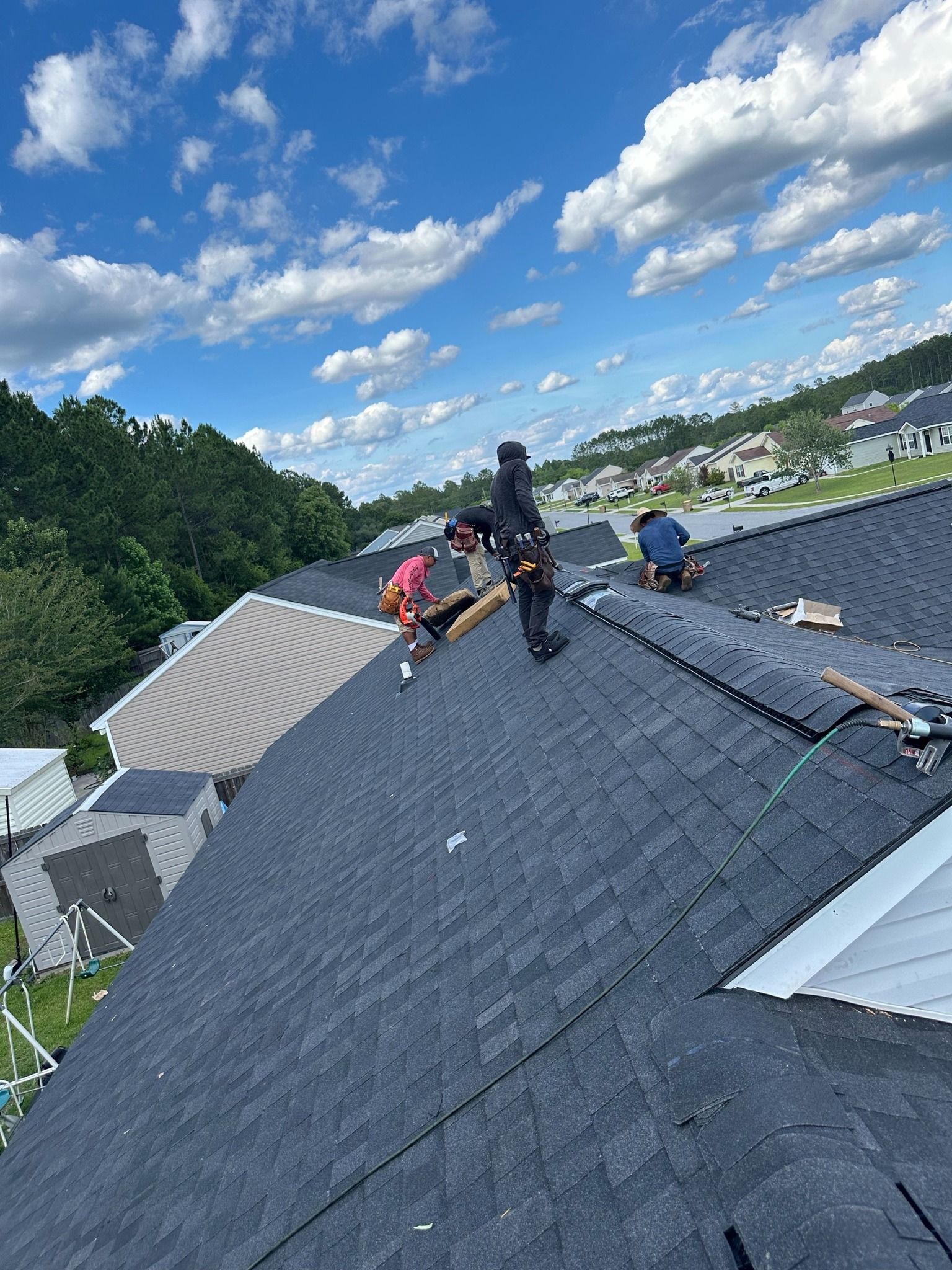 A group of people are working on the roof of a house.