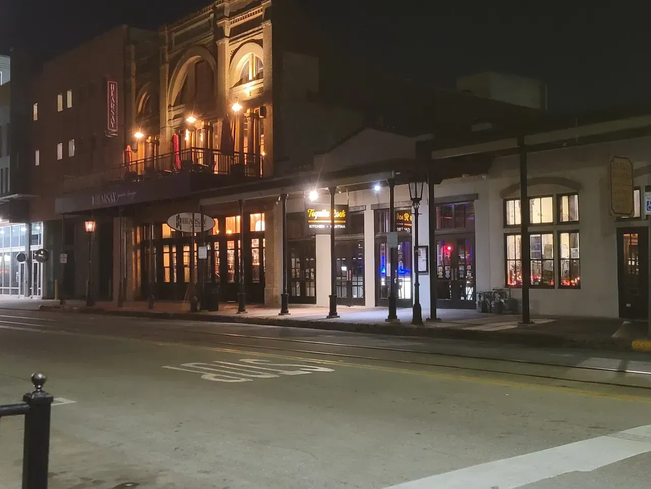 A city street at night with a large building in the background