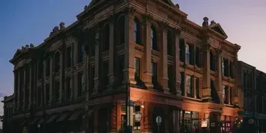 A large brick building with a lot of windows is lit up at night.