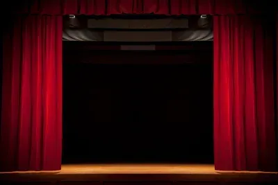 An empty stage with red curtains and spotlights.