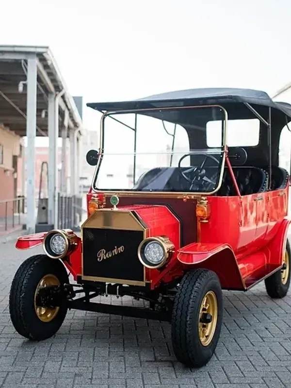 A red retro car is parked on a brick sidewalk
