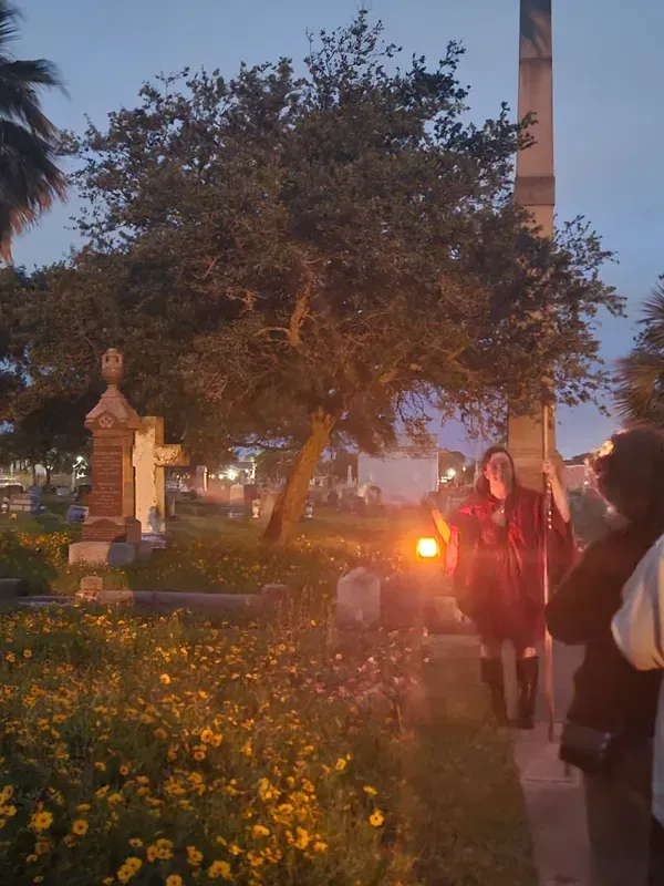 A group of people are walking through a cemetery at night.