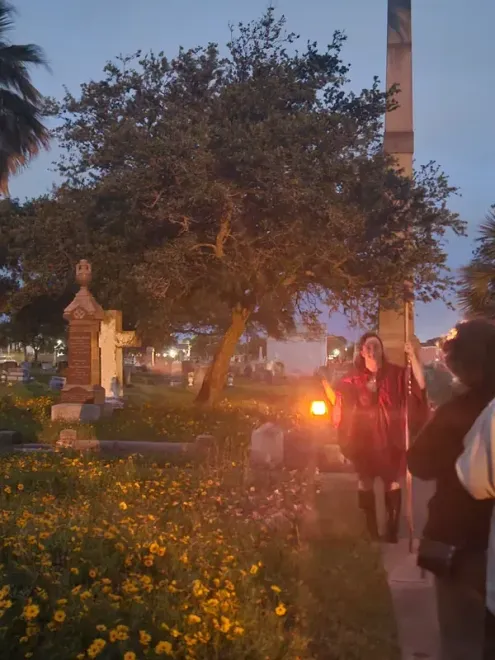A group of people are walking through a cemetery at night.