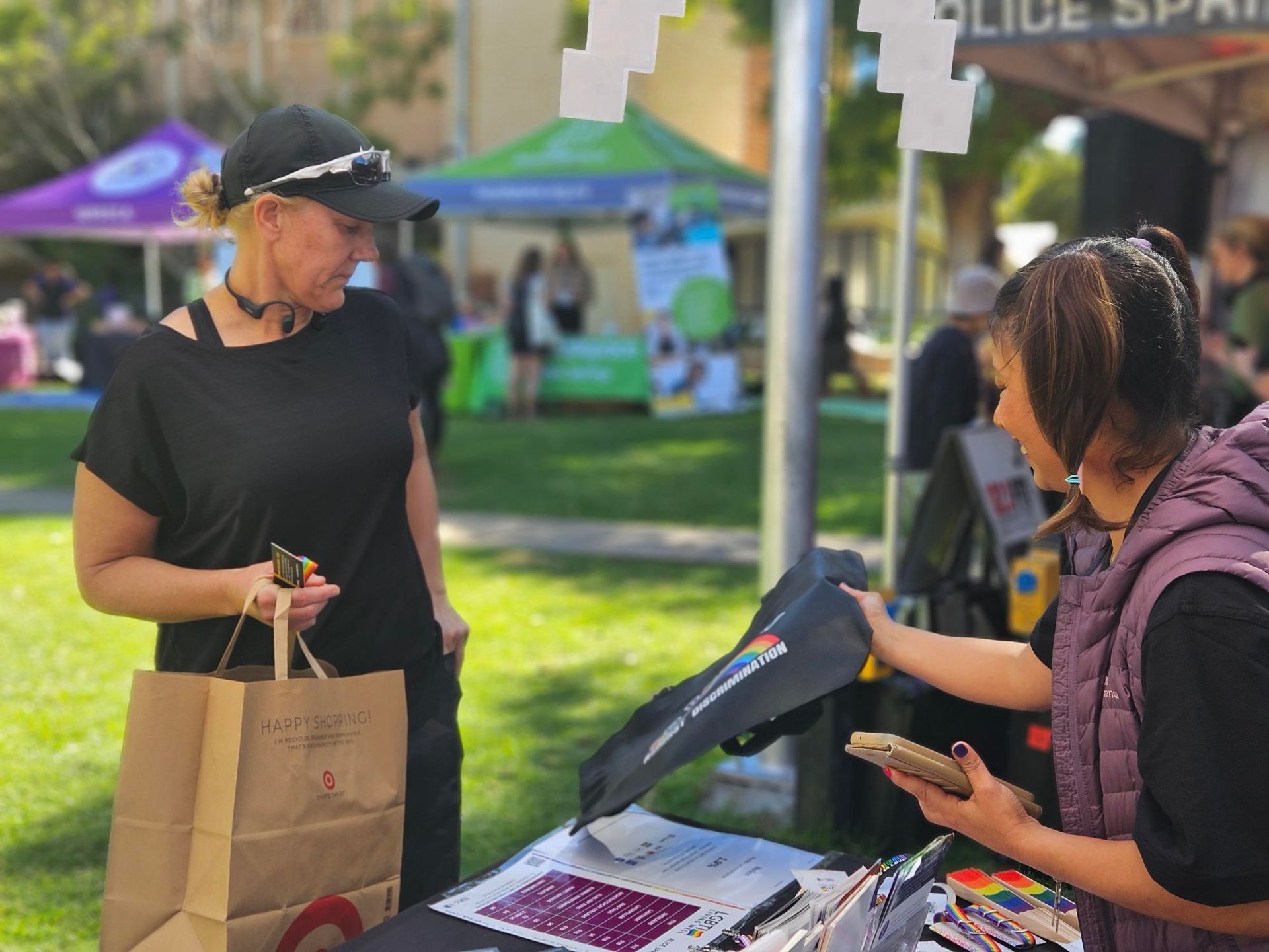 Two women are standing at a table talking to each other.