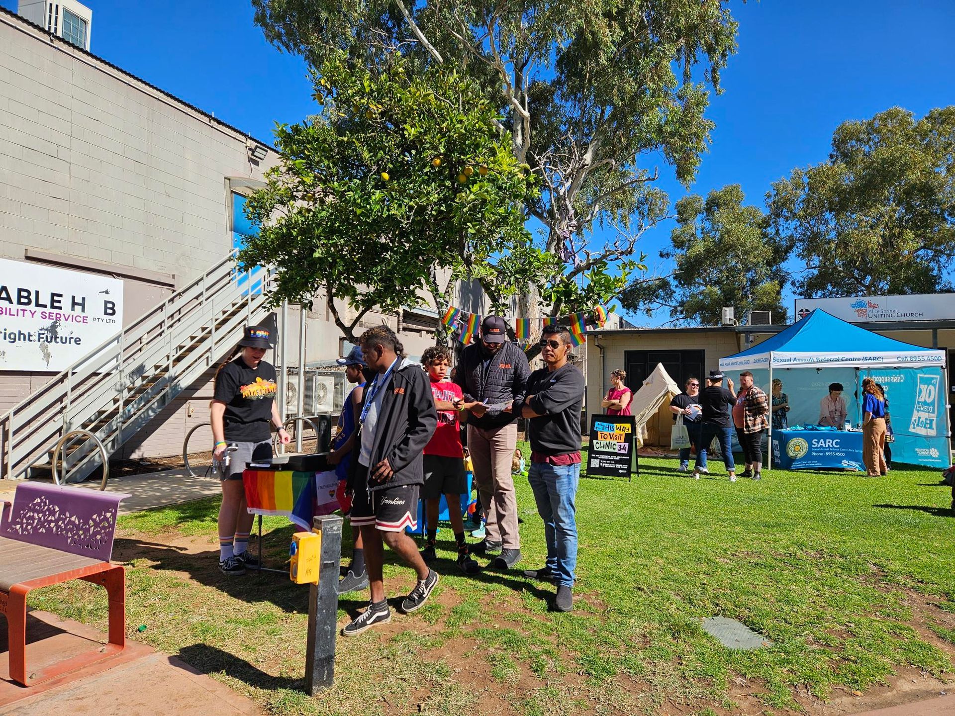 A group of people are standing in a grassy area in front of a building.