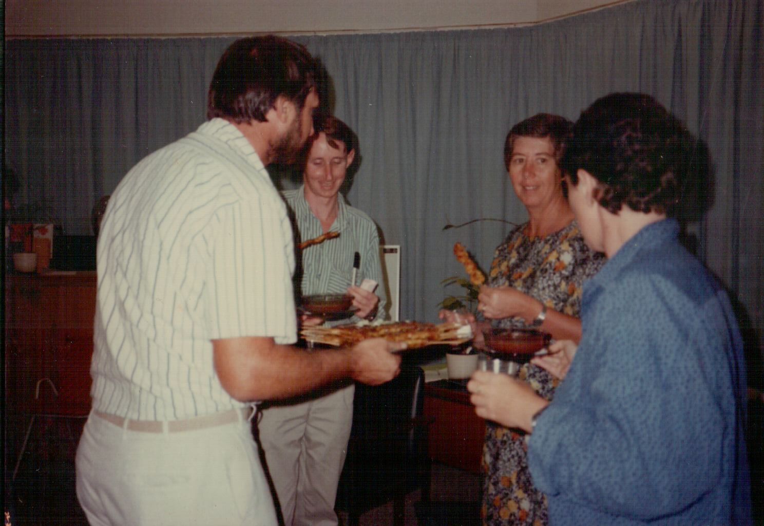 A man is holding a tray of food in front of a group of people.