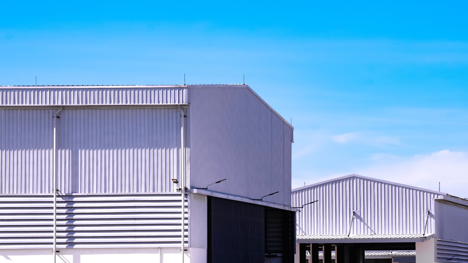 Metal warehouses against a bright blue sky.
