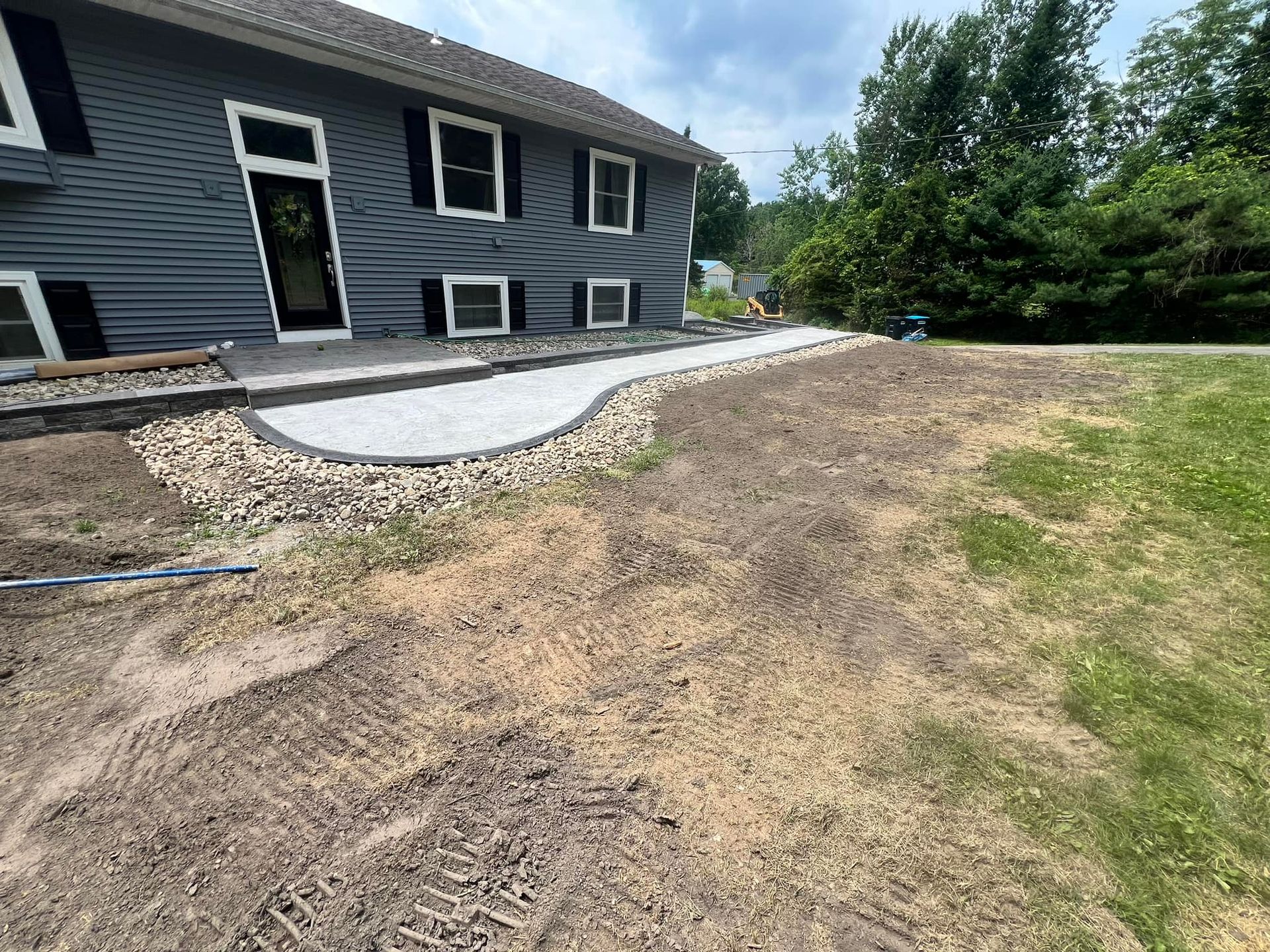 A gray house with a concrete walkway in front of it.