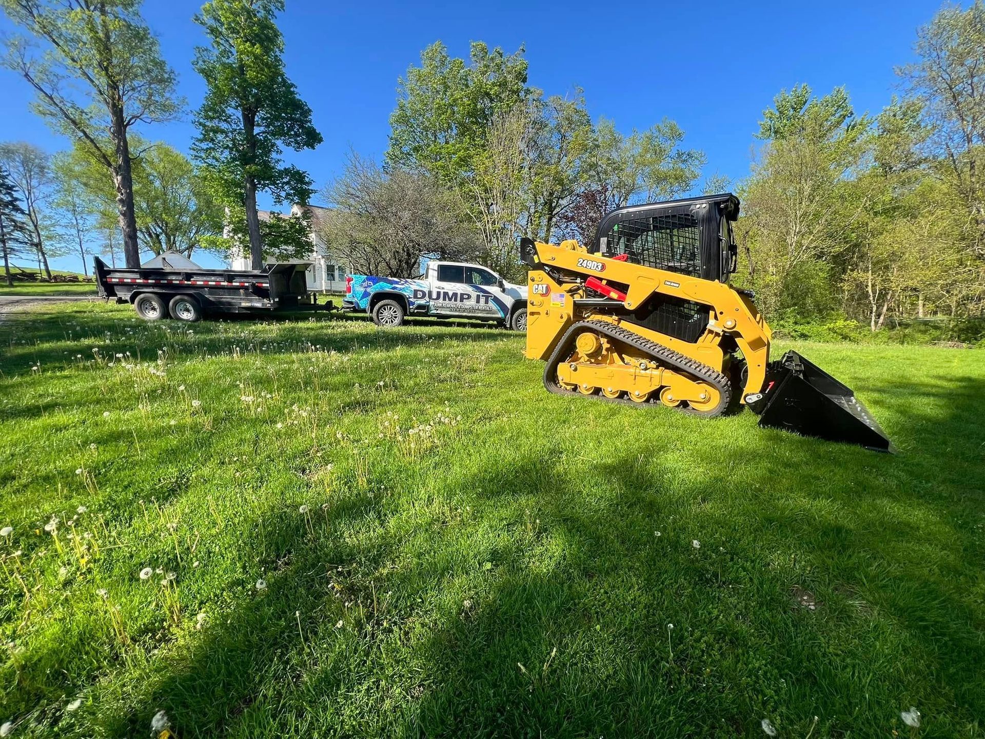 A bulldozer is parked in a grassy field next to a truck.