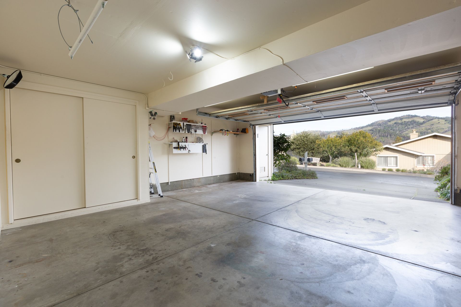 An empty garage with the door open and a view of the street.