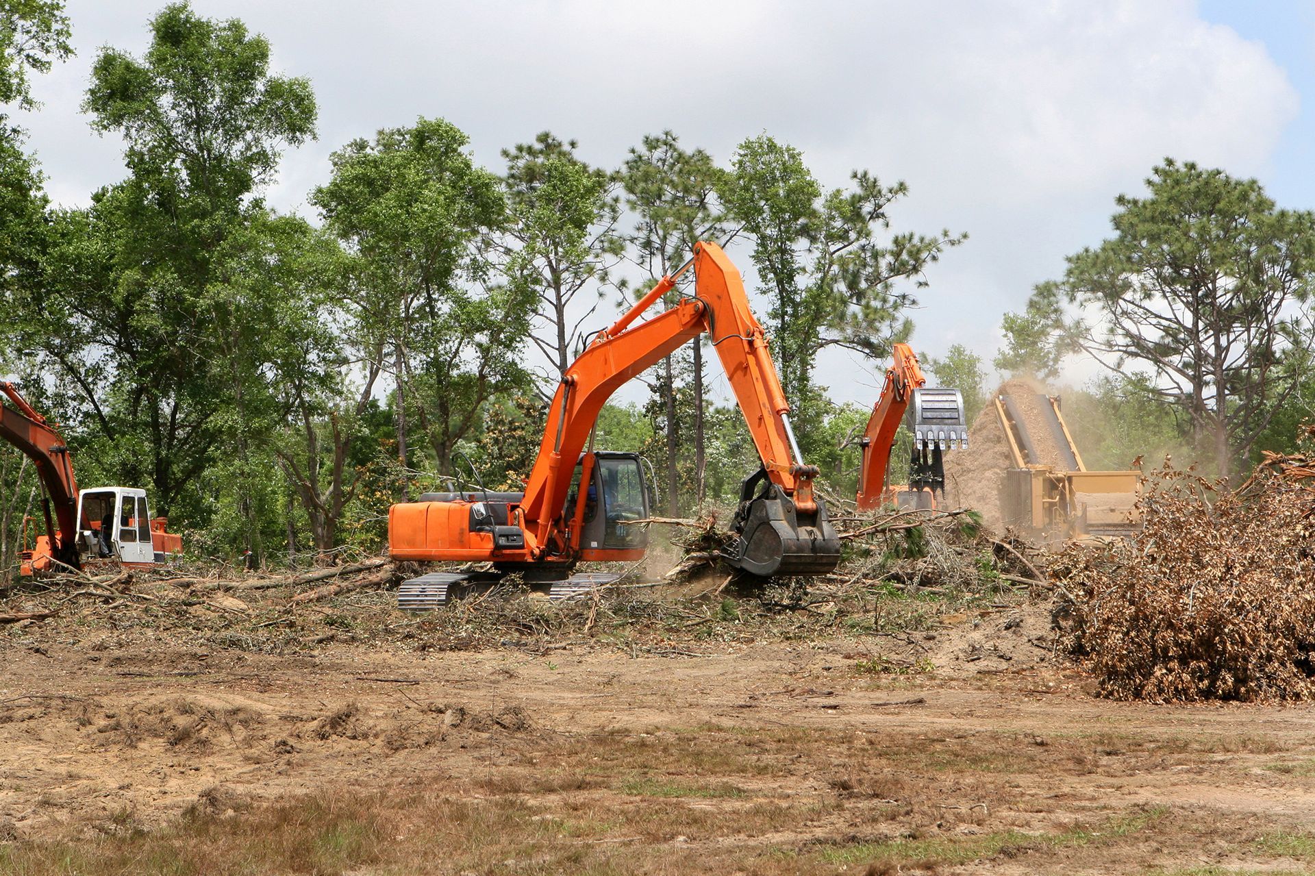 A couple of excavators are working on a dirt field.