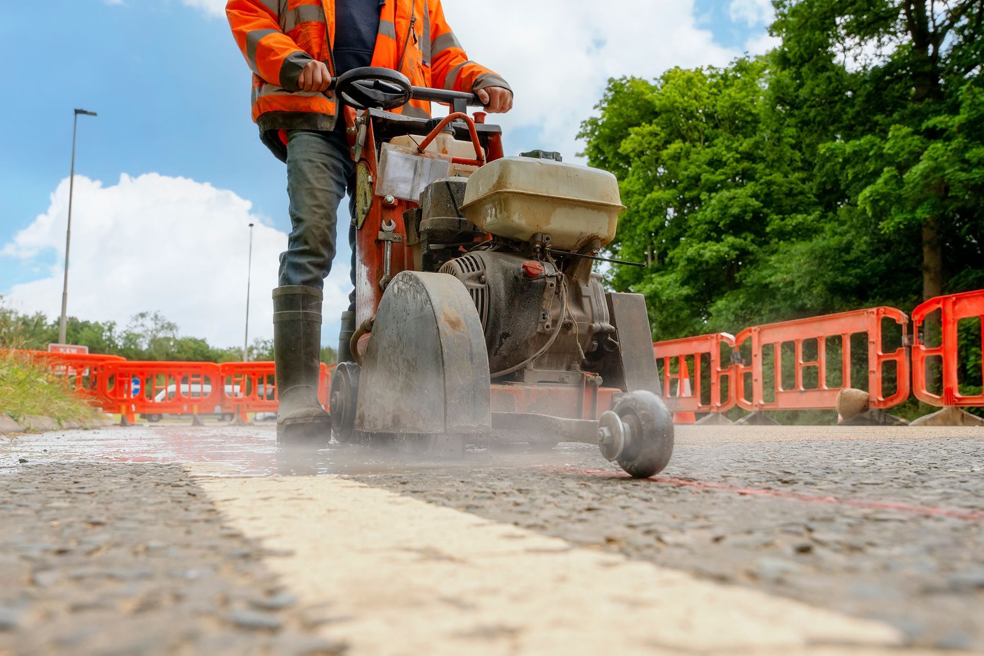 A man is using a concrete saw to cut a road.