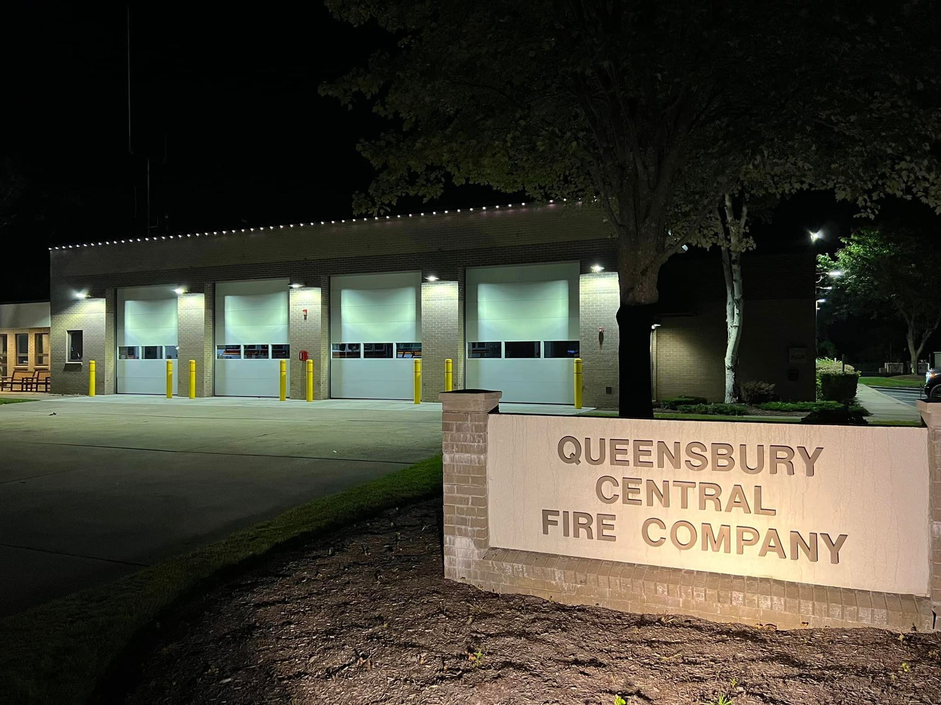 The queensbury central fire company is lit up at night.