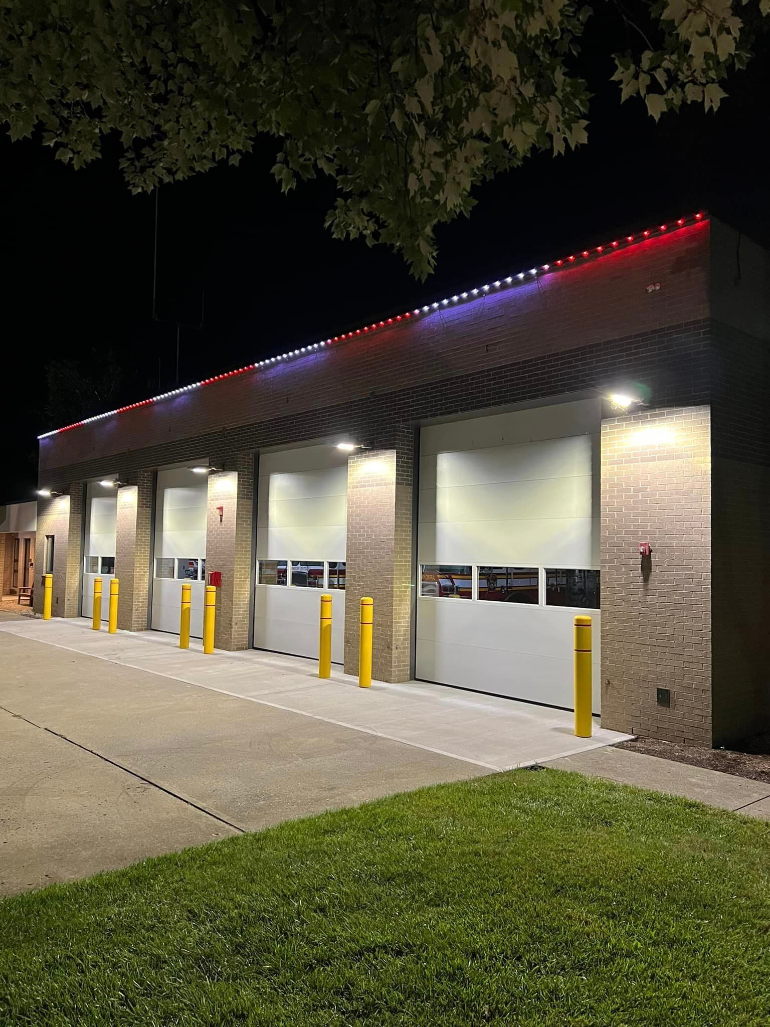 A fire station is lit up at night with red , white and blue lights.