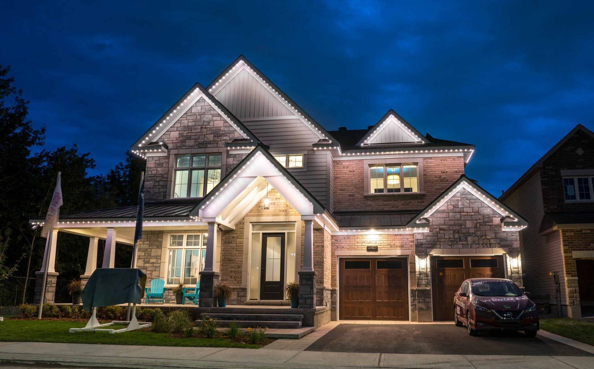 A large house is lit up at night with a car parked in front of it.