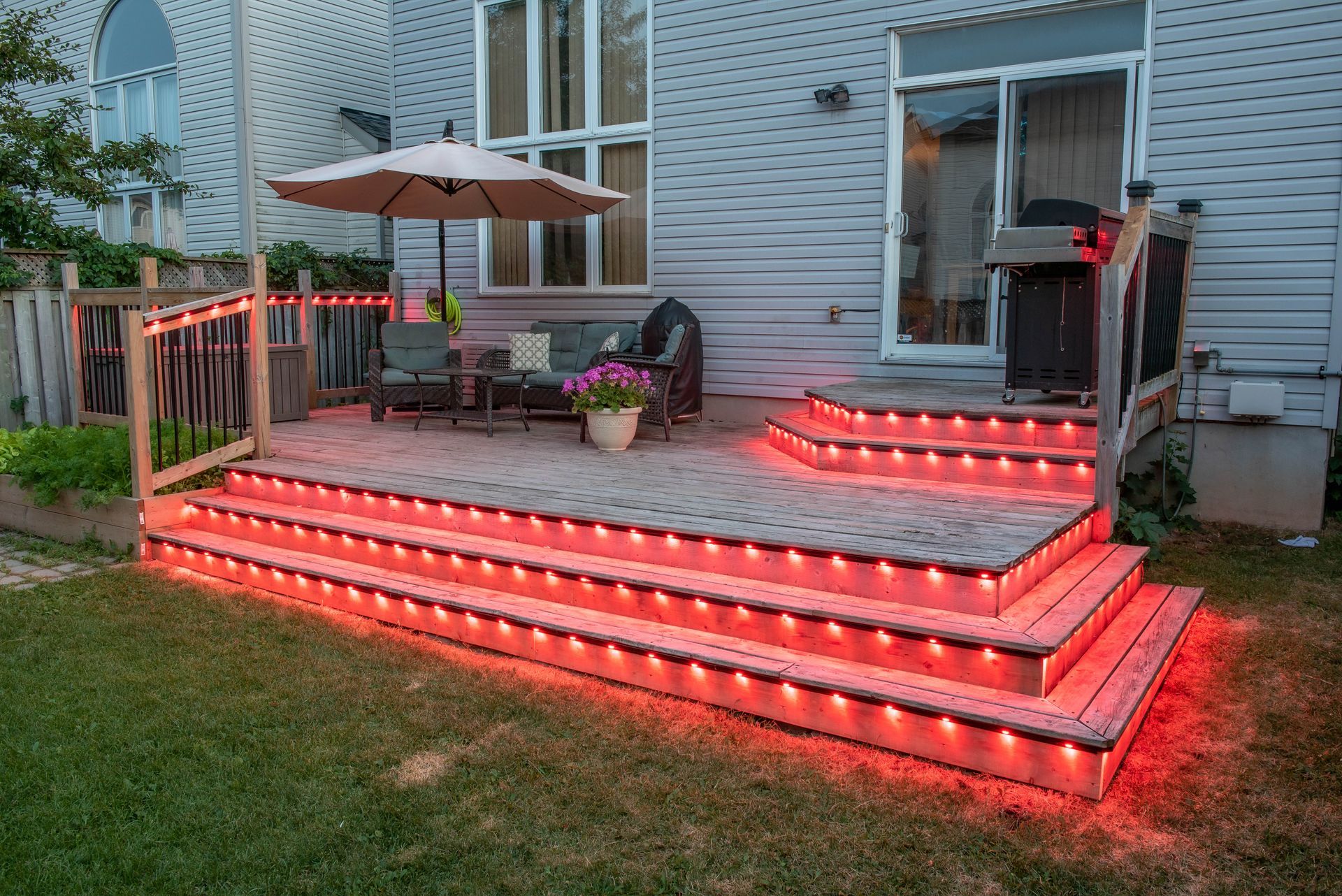 A deck with red lights on it and a house in the background.