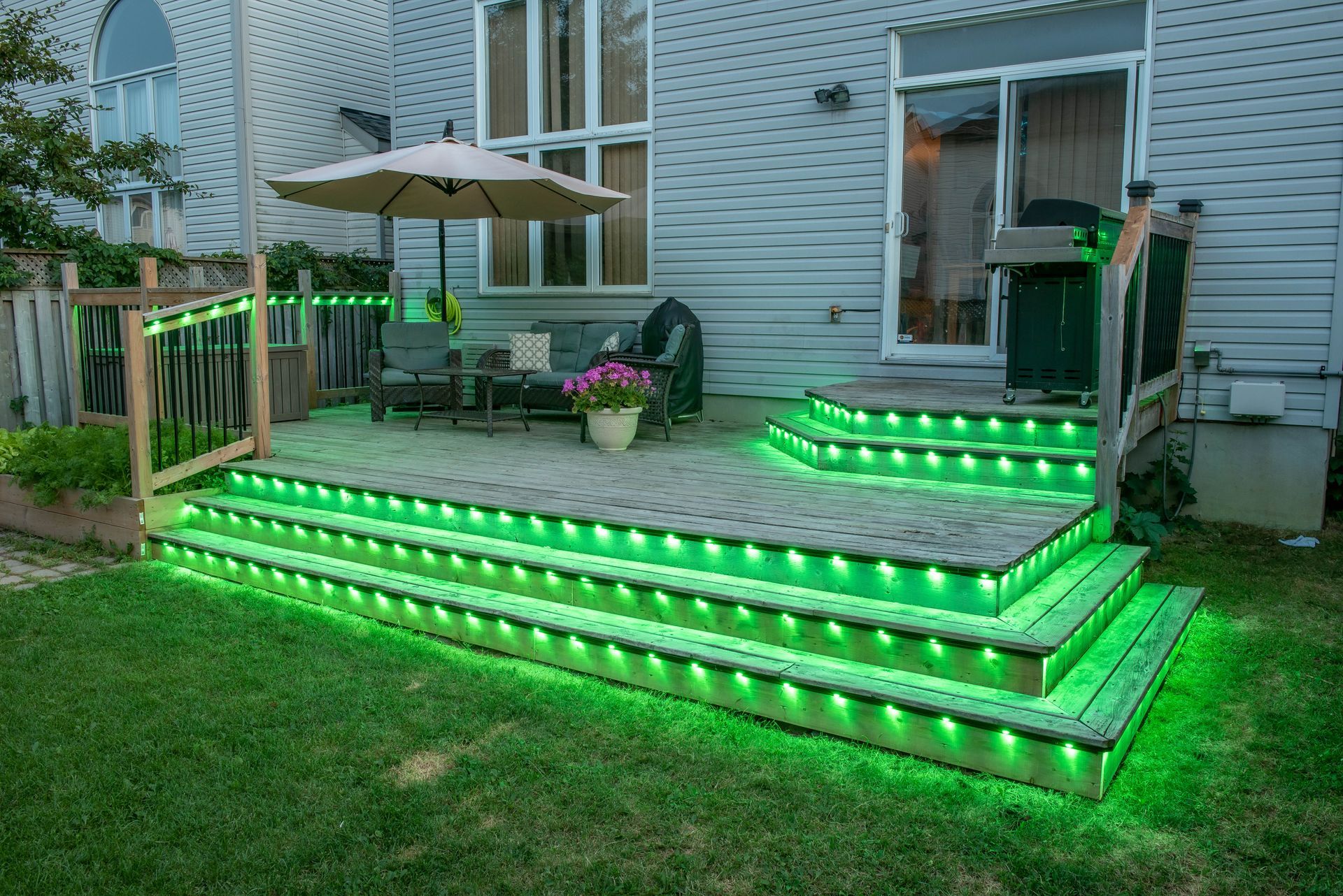 A deck with green lights on it and a house in the background.