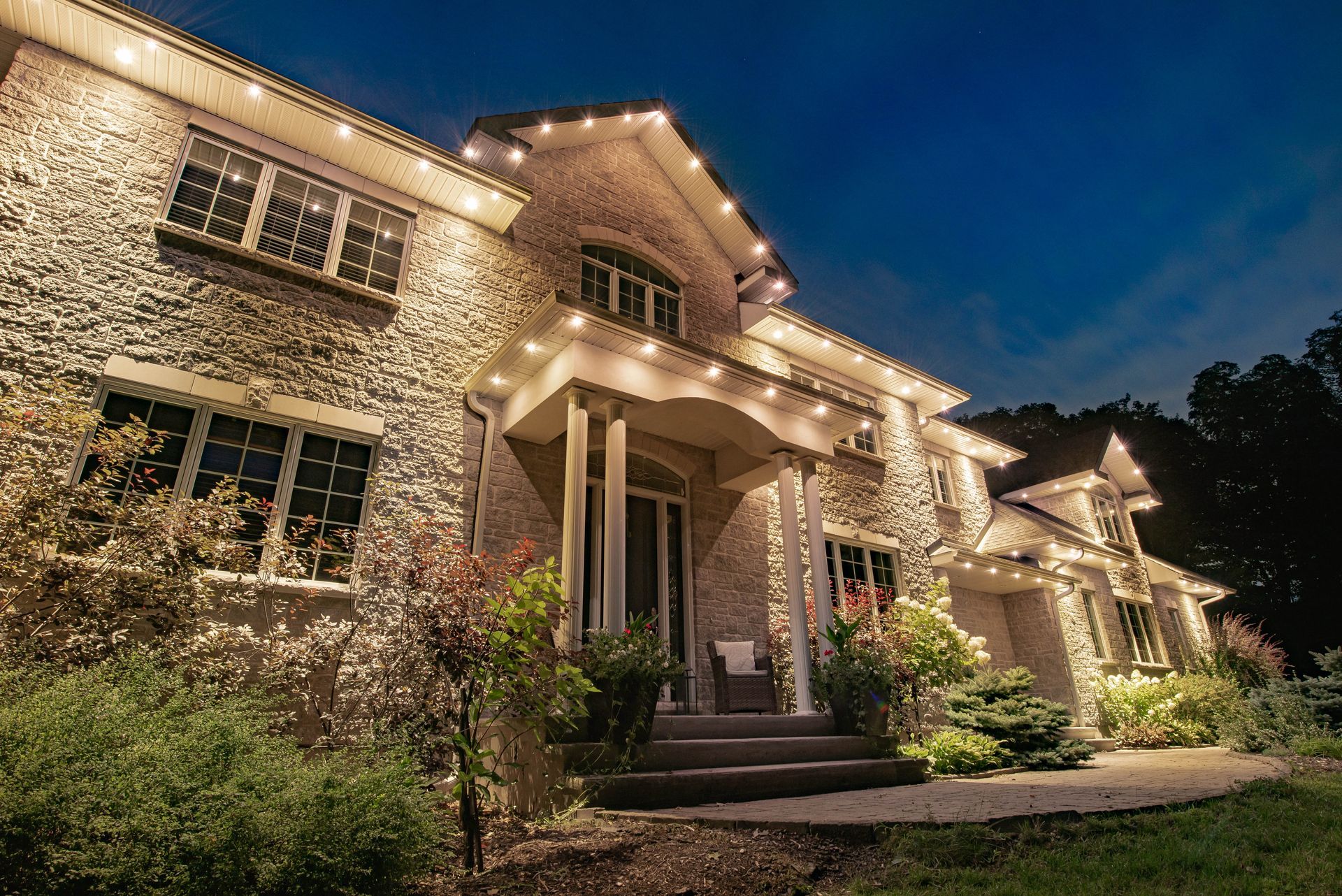 A large stone house is lit up at night with christmas lights.