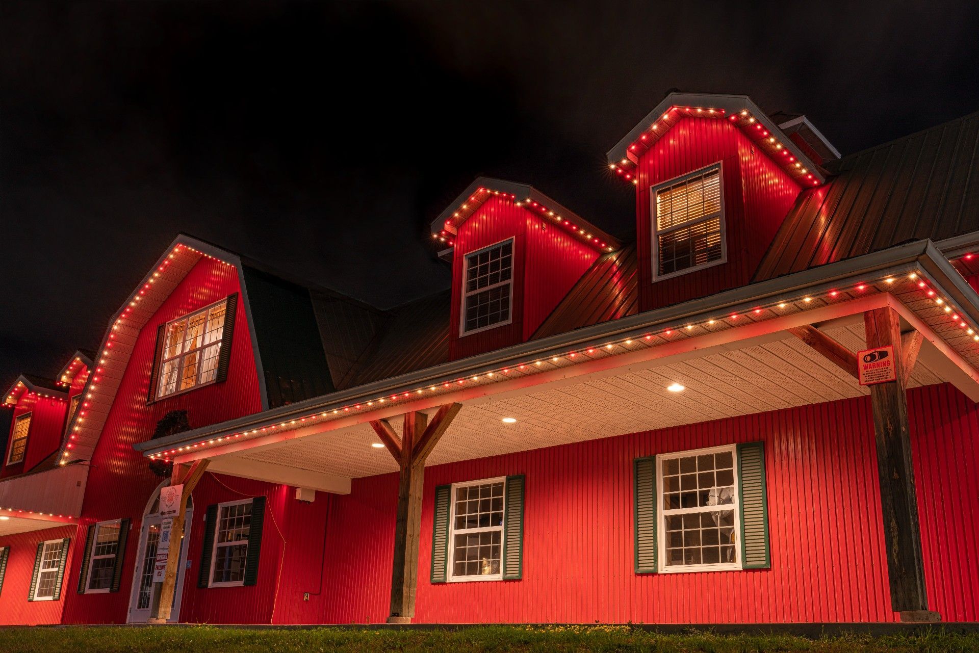 A red barn is decorated with christmas lights at night.