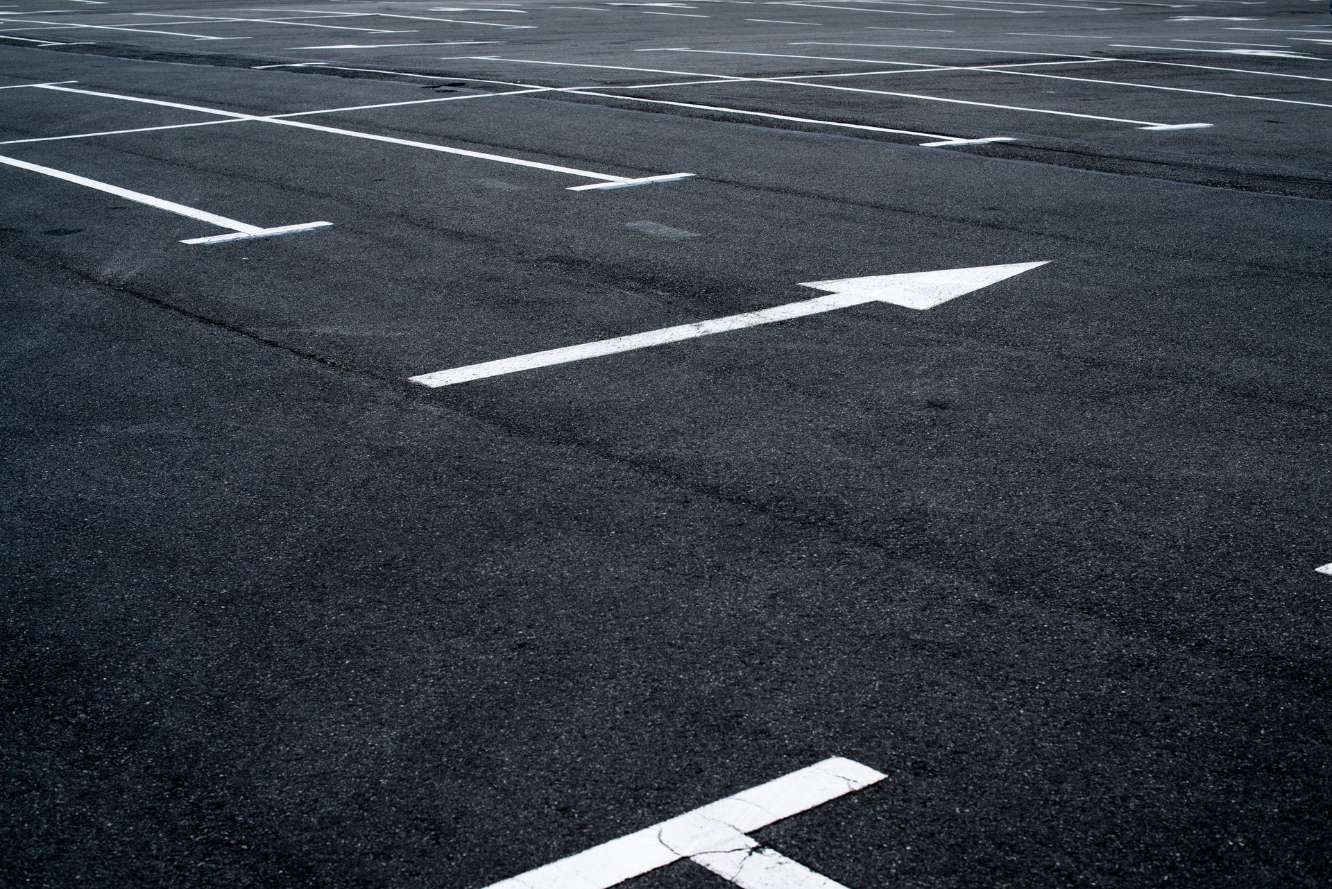 A parking lot with white arrows painted on the asphalt.