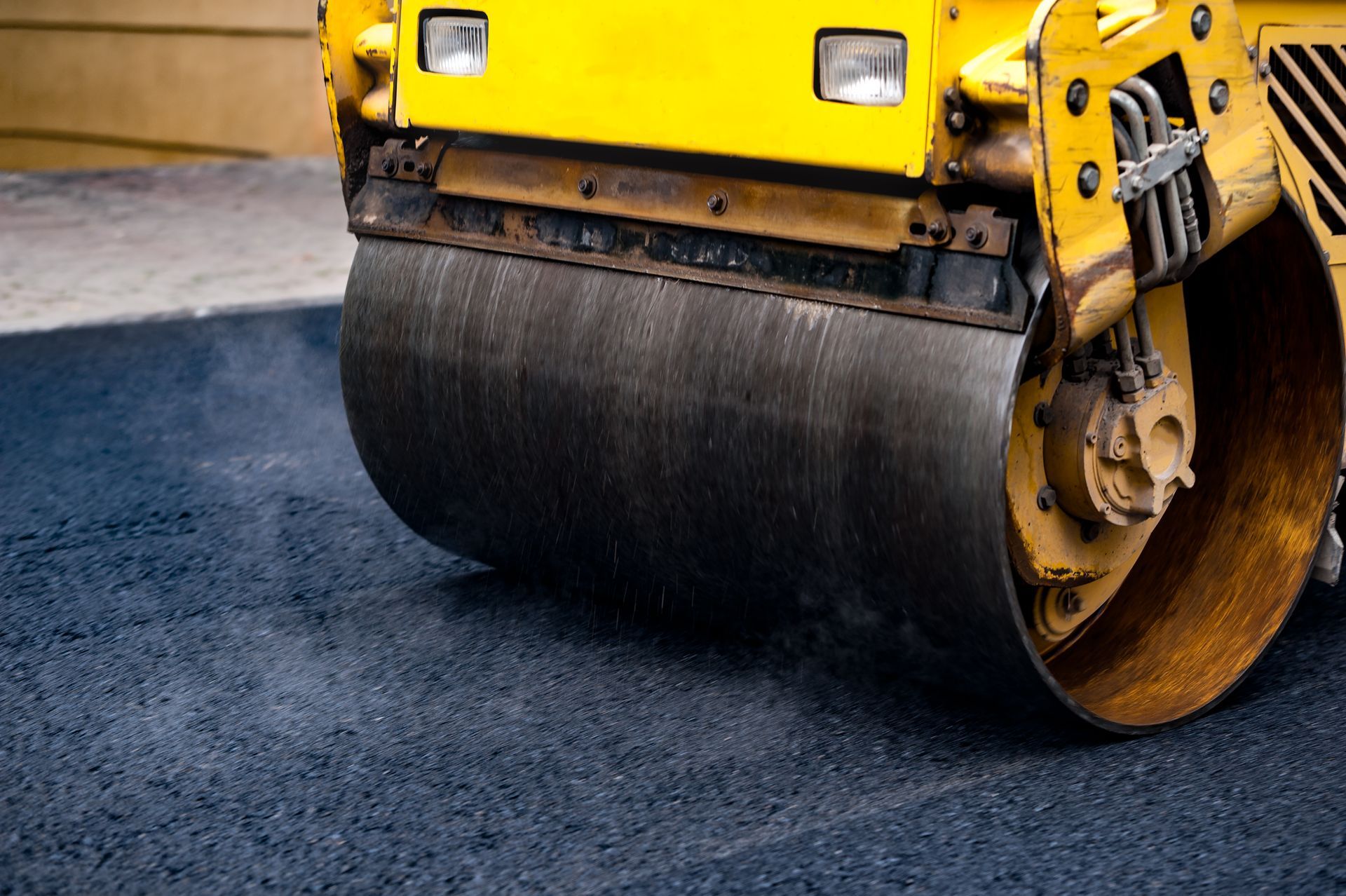 A yellow roller is rolling asphalt on a road.