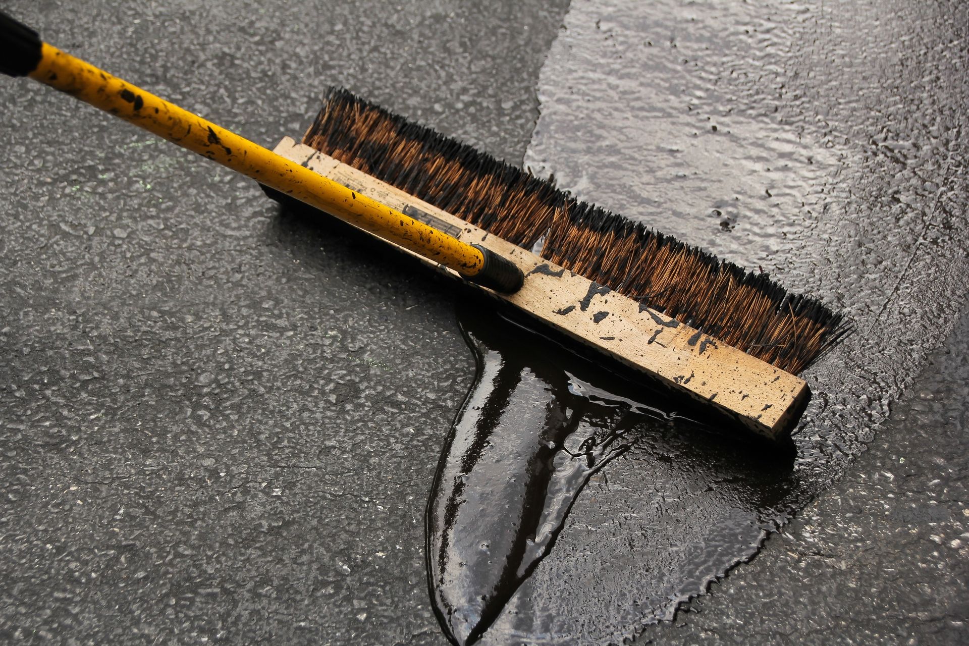 A yellow broom is being used to clean a wet floor