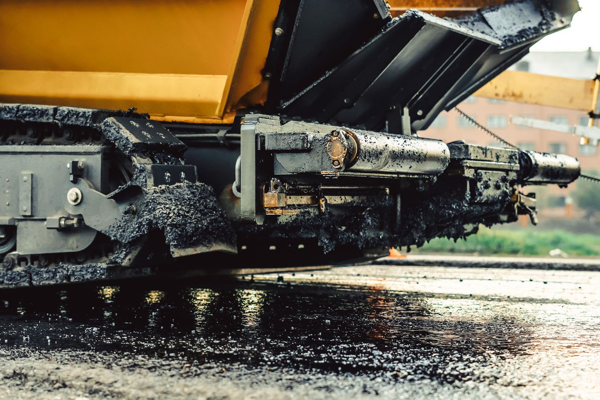 A close up of an asphalt paving machine on a road.