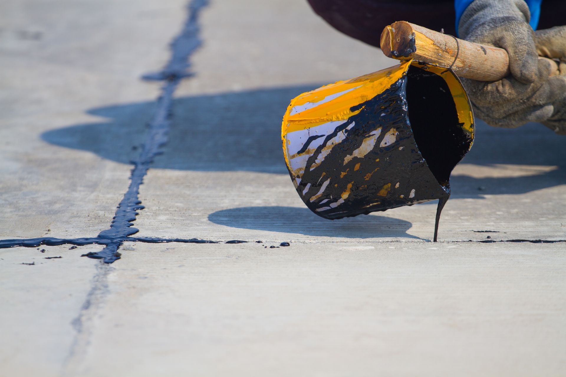 A person is pouring liquid from a bucket onto a concrete surface.