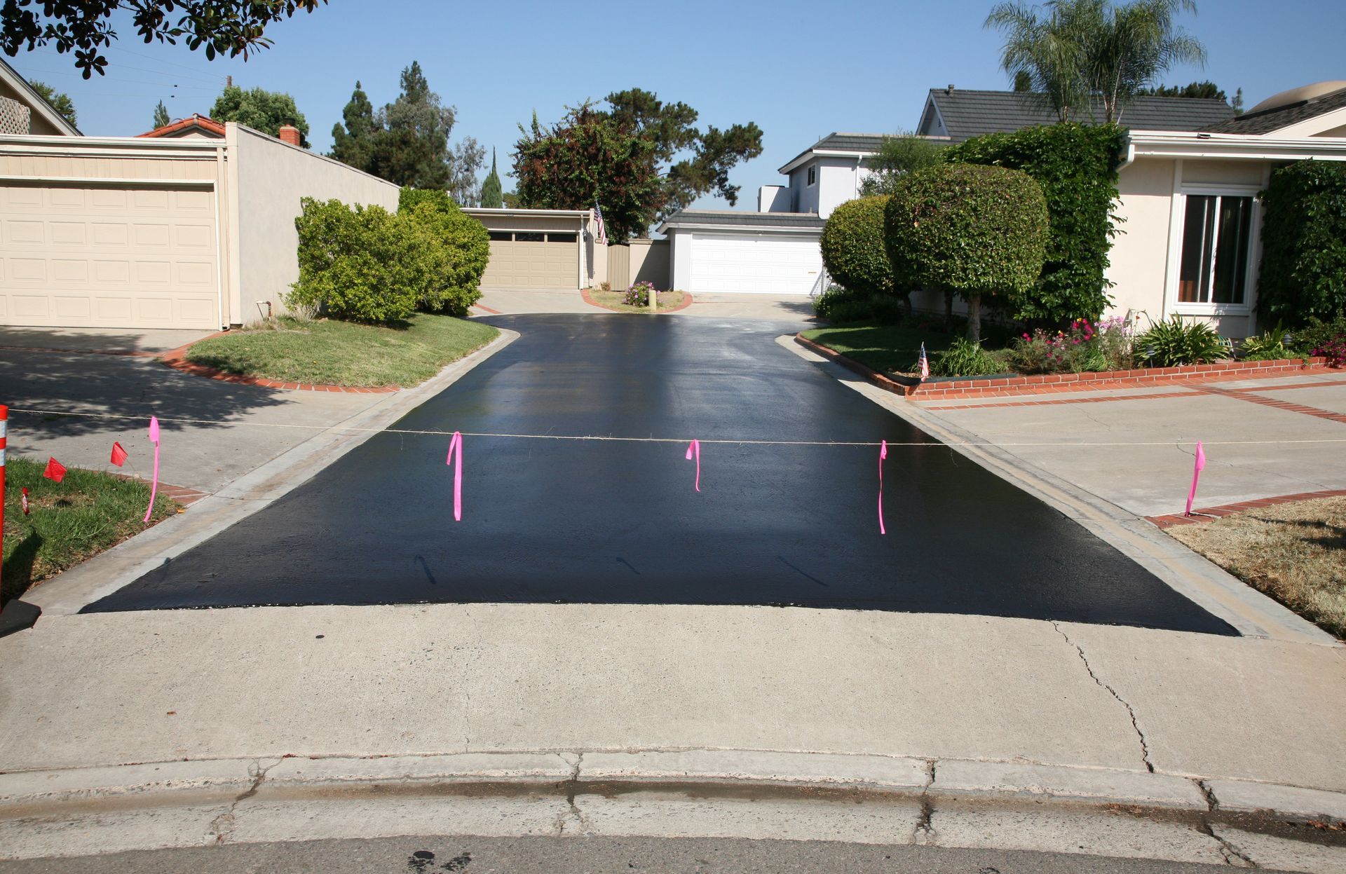 A residential driveway with a few pink markers on it