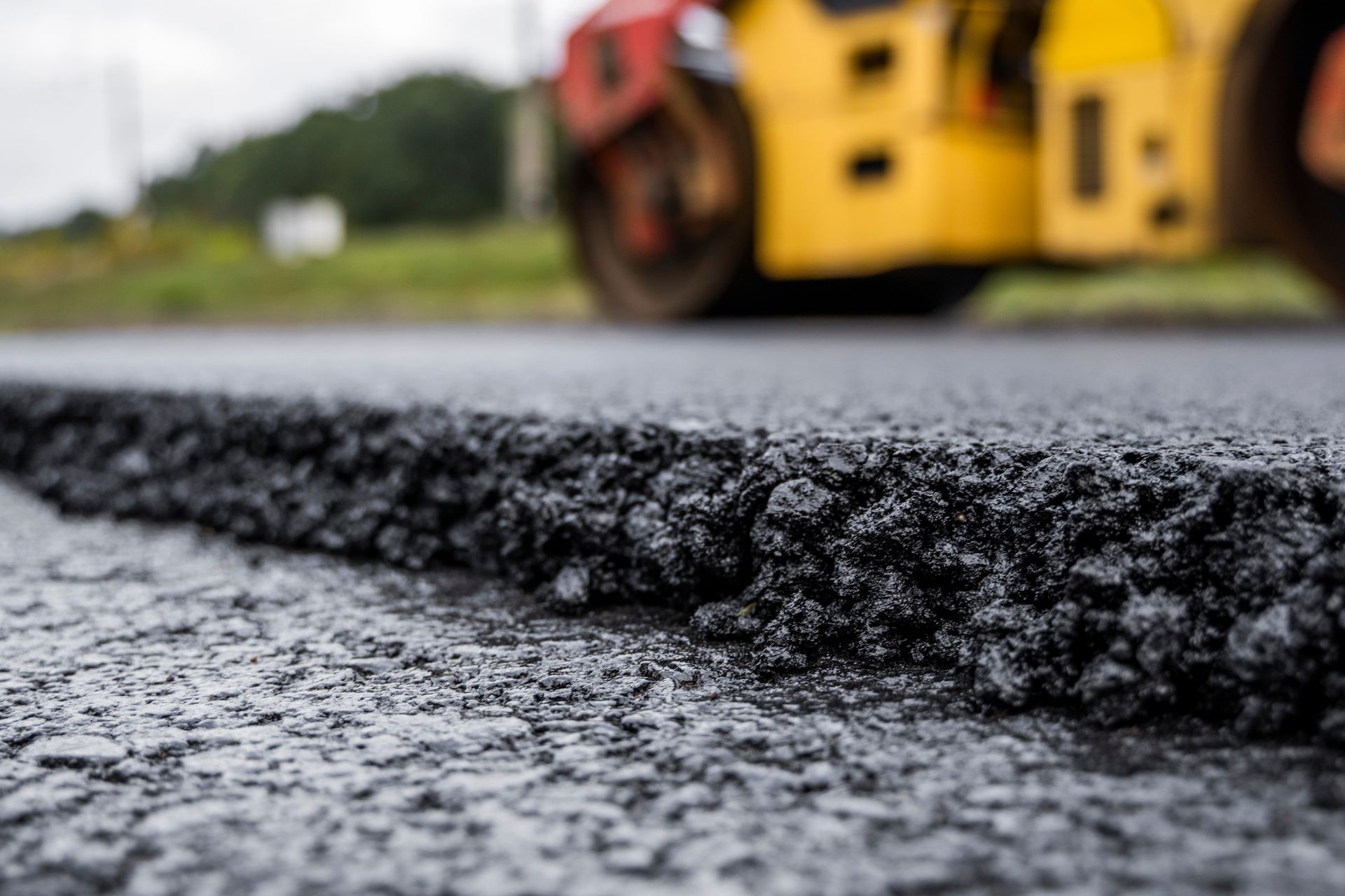 A yellow roller is rolling asphalt on a road.