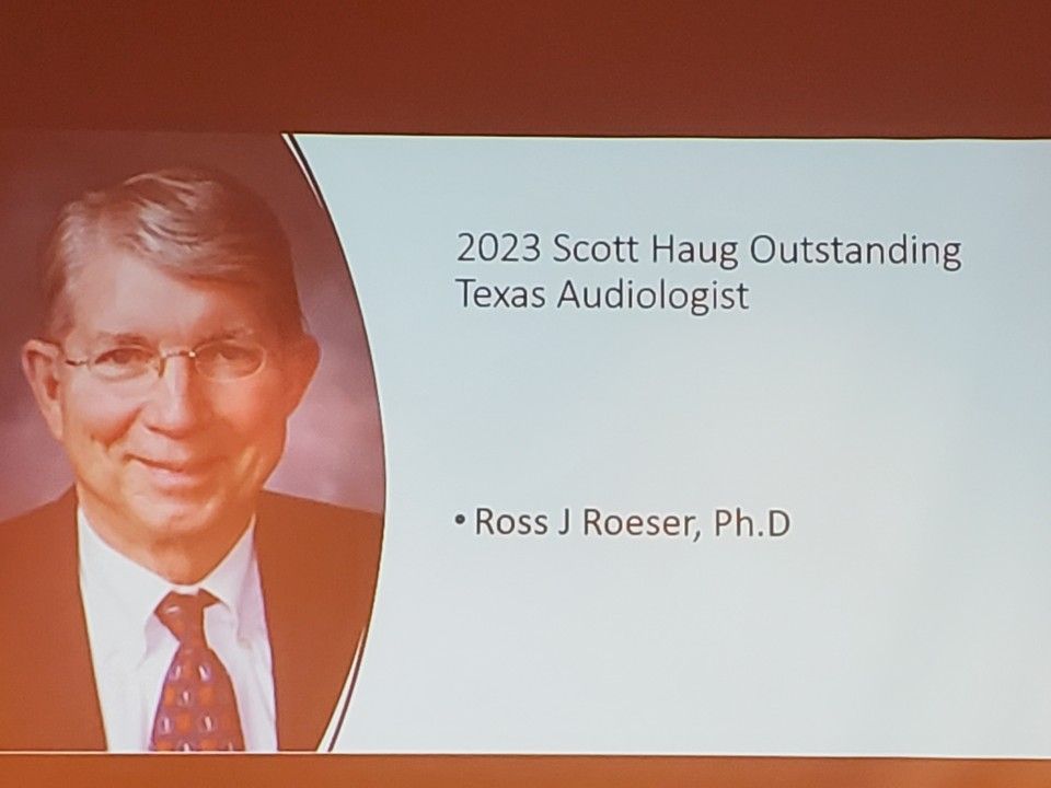 Ross J. Roeser, Ph.D, smiles on a slide. Text: 2023 Scott Haug Outstanding Texas Audiologist.