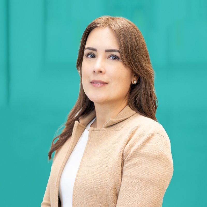 Woman with long, light brown hair smiles at the camera, wearing a maroon top against a white backdrop.