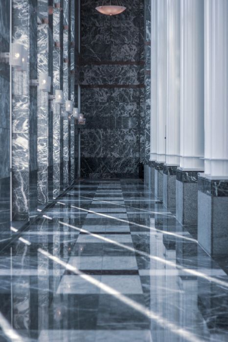 A long hallway with marble floors and columns in a building.