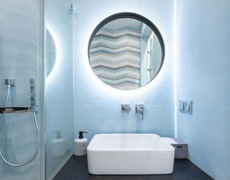 A beautifully tiled bathroom with a sink , mirror and shower.