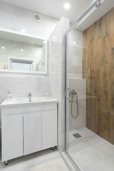 A bathroom with a sink , mirror and walk in shower. Expertly tiled by Orchid Tiling.