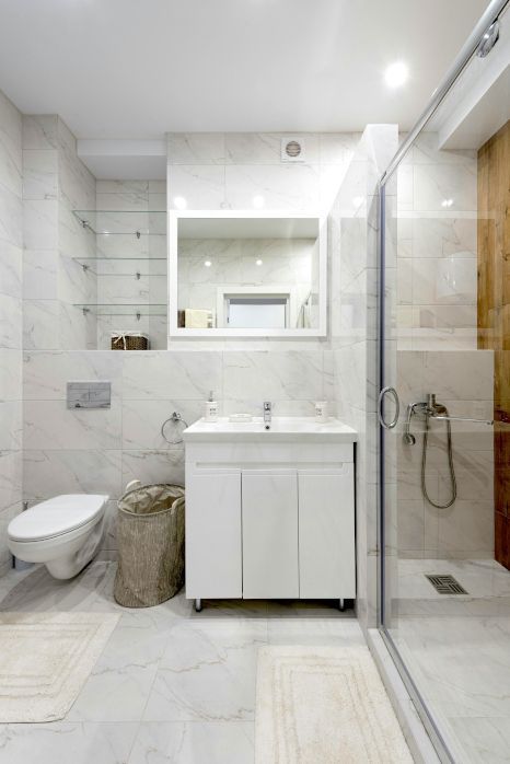 A bathroom with a sink , mirror and walk in shower. Expertly tiled by Orchid Tiling.